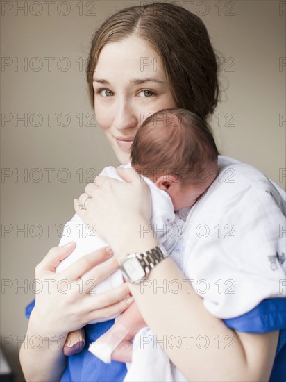 Portrait of young female nurse holding baby boy (2-5 months). 
Photo : Jessica Peterson