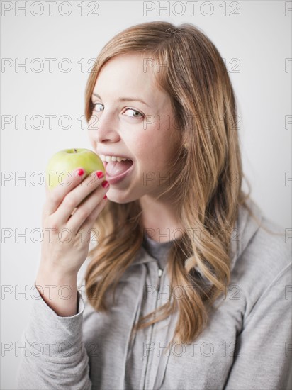 Portrait of attractive young woman holding green apple. 
Photo : Jessica Peterson