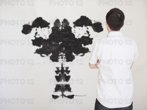 Man looking at black complex shape painted on wall. 
Photo: Jessica Peterson