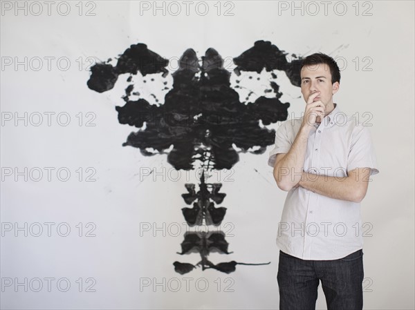 Man looking standing in front of complex shape painted on wall. 
Photo : Jessica Peterson