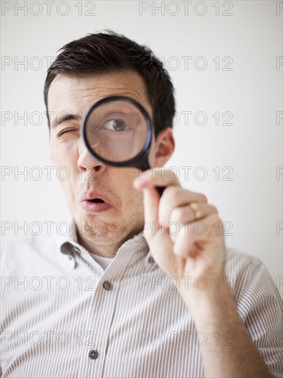 Man looking through magnifying glass. 
Photo: Jessica Peterson