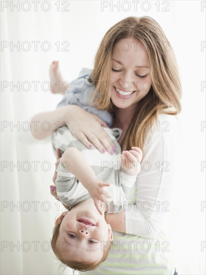 Portrait of young woman embracing baby boy (6-11 months) upside-down. 
Photo: Jessica Peterson