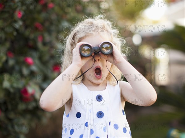 Surprised young girl (4-5) looking through binoculars. 
Photo: Jessica Peterson