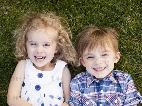 Outdoor portrait of girl (4-5) and boy (6-7) lying on grass.
Photo : Jessica Peterson
