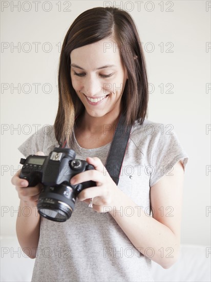 Young woman playing with digital camera. 
Photo : Jessica Peterson
