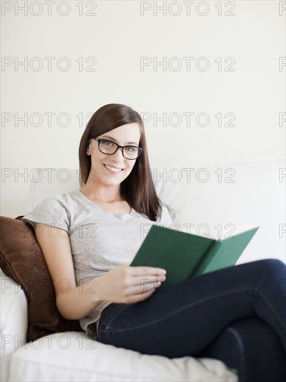 Young attractive woman sitting on sofa, reading. 
Photo : Jessica Peterson