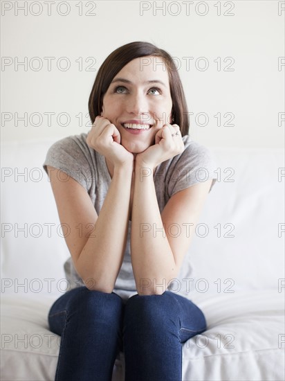 Happy young woman sitting on bed. 
Photo: Jessica Peterson