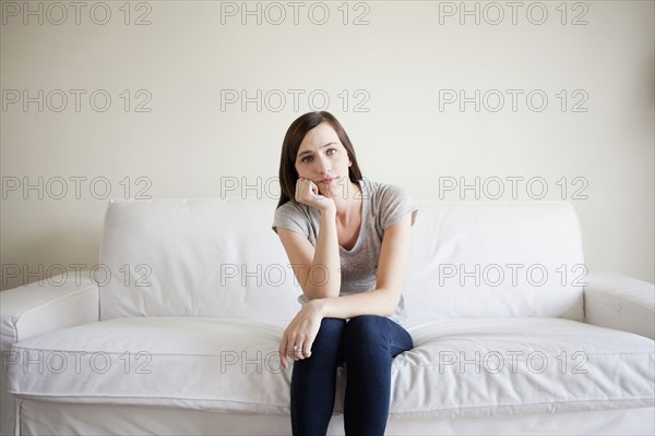 Bored young woman sitting on bed. 
Photo : Jessica Peterson