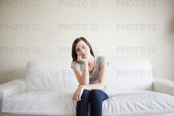 Bored young woman sitting on bed. 
Photo : Jessica Peterson