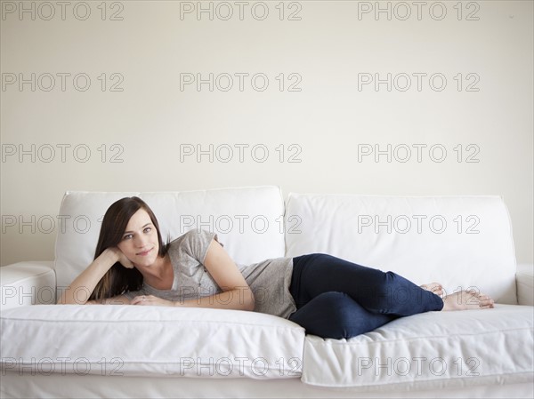 Happy young woman reclining on bed. 
Photo : Jessica Peterson