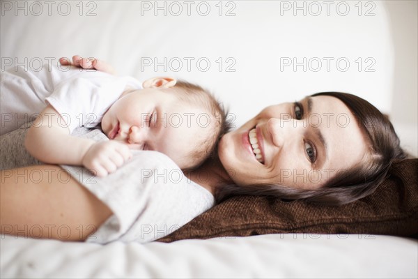 Mother embracing sleeping baby girl (2-5 months) . 
Photo : Jessica Peterson