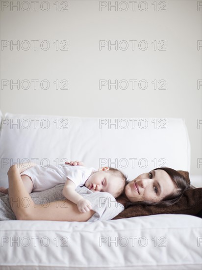 Mother embracing sleeping baby girl (2-5 months) . 
Photo : Jessica Peterson