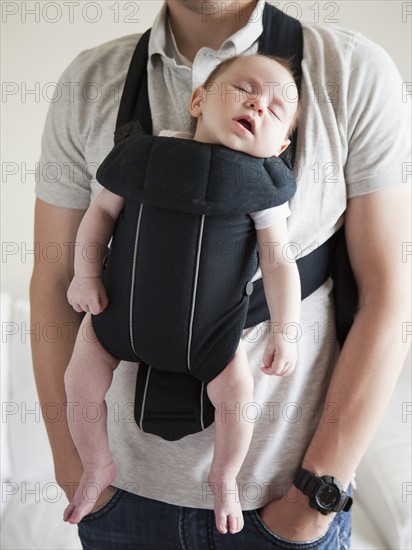 Young father holding baby daughter (2-3 months) in carrycot. 
Photo: Jessica Peterson