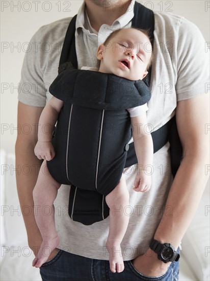 Young father holding baby daughter (2-3 months) in carrycot.
Photo : Jessica Peterson