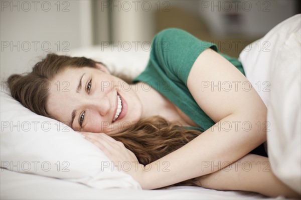 Portrait of happy young woman lying in bed.
Photo : Jessica Peterson