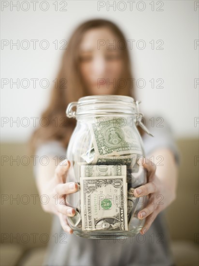 Young woman presenting her savings jar . 
Photo: Jessica Peterson