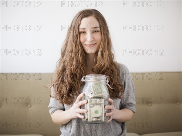 Young woman presenting her savings jar . 
Photo : Jessica Peterson