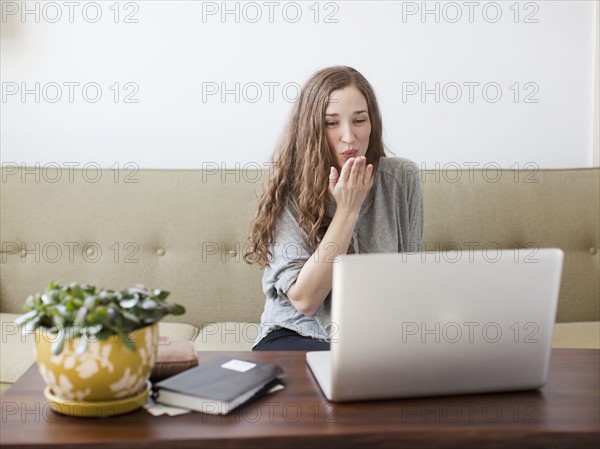 Young woman blowing kiss while using laptop. 
Photo : Jessica Peterson