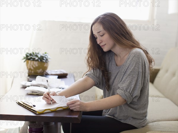 Young woman going though domestic paperwork. 
Photo: Jessica Peterson