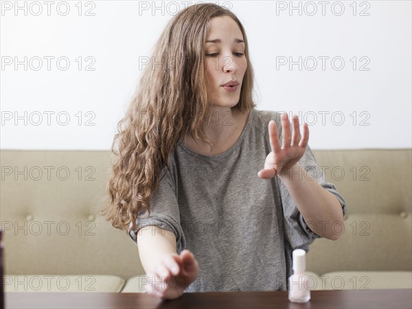 Young woman painting fingernails. 
Photo : Jessica Peterson