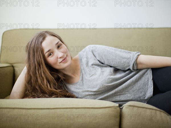 Happy young woman reclining on sofa. 
Photo: Jessica Peterson