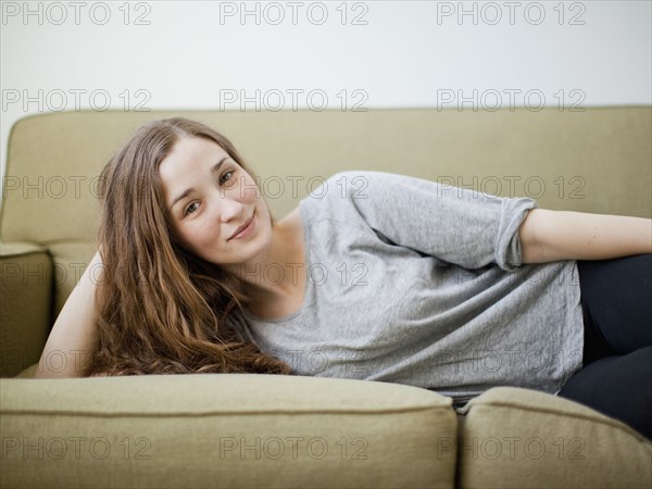 Happy young woman reclining on sofa. 
Photo : Jessica Peterson