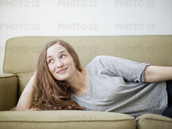 Happy young woman reclining on sofa.
Photo : Jessica Peterson