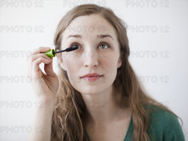 Attractive young woman applying mascara. 
Photo : Jessica Peterson
