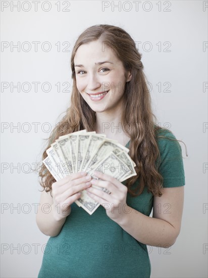 Attractive young woman holding fan made up from us dollar banknotes. 
Photo : Jessica Peterson