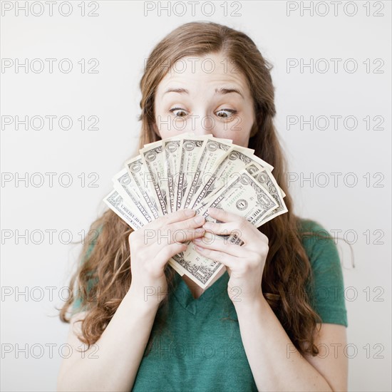 Excited young woman holding fan made up from us dollar banknotes. 
Photo: Jessica Peterson