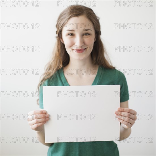 Portrait of young attractive woman holding blank sheet of paper. 
Photo : Jessica Peterson