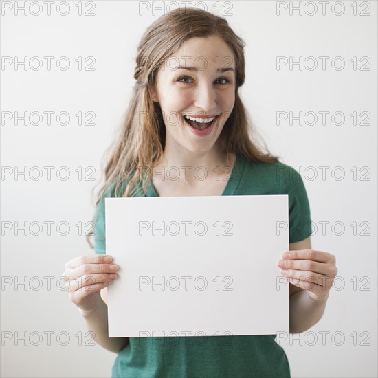 Portrait of young attractive woman holding blank sheet of paper. 
Photo : Jessica Peterson