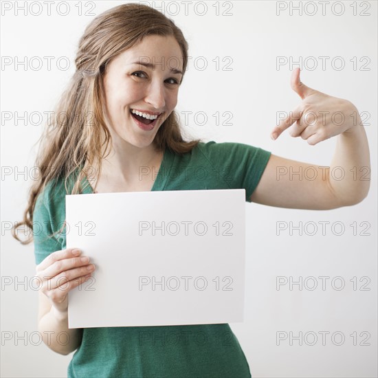 Portrait of young attractive woman holding blank sheet of paper. 
Photo : Jessica Peterson