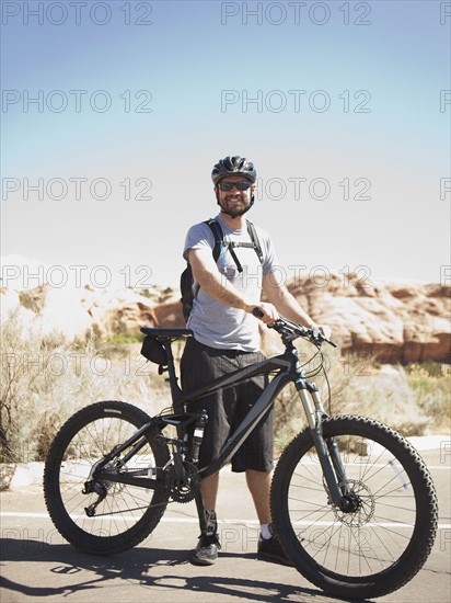 USA, Utah, Moab, Mid adult man posing with mountain bicycle in remote scenery. 
Photo : Jessica Peterson