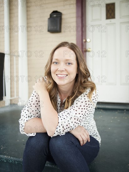 Portrait of happy young woman sitting on porch.
Photo : Jessica Peterson