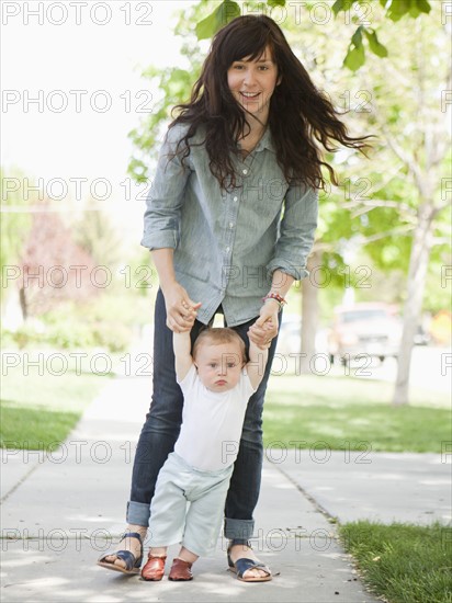 Young mother assisting baby boy (6-11 months) in his first steps. 
Photo : Jessica Peterson