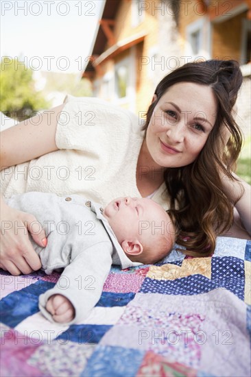 Young mother with baby boy ( 2-5 months) lying on blanket. 
Photo: Jessica Peterson
