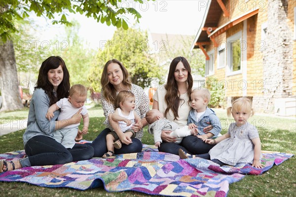 USA, Utah, Salt Lake City, Three young mothers with two baby boys (6-11 months), toddler boy and girl (2-3) sitting in park. 
Photo: Jessica Peterson