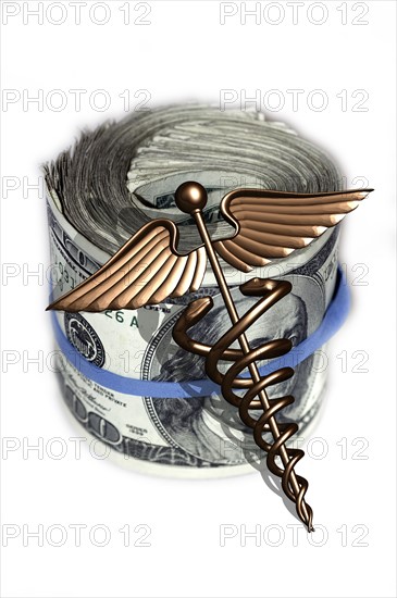 Caduceus and wad of us dollar bills. 
Photo : Calysta Images