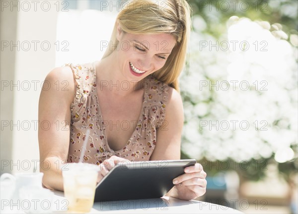 Woman using tablet pc at outdoor cafe table.