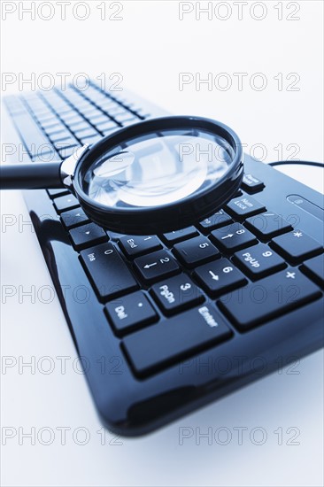 Magnifying glass over computer keyboard.