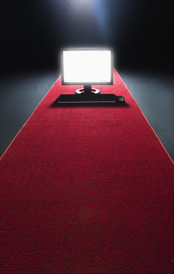 Studio shot of glowing computer on red carpet.