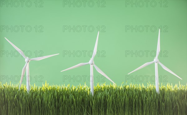 Model wind turbines in grass on green background.