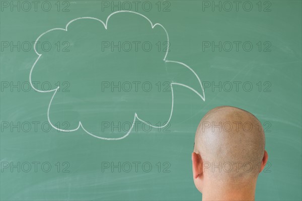 Man in front of blackboard with drawing depicting speech bubble.