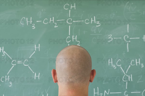 Man in front of blackboard with formulas.