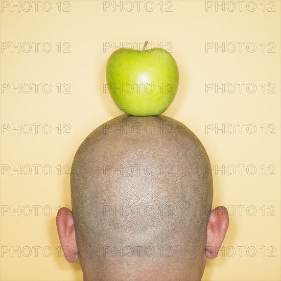 Back view of man with apple on head.