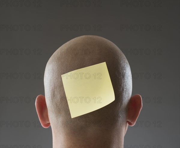 Back view of man with adhesive note on shaved head.
