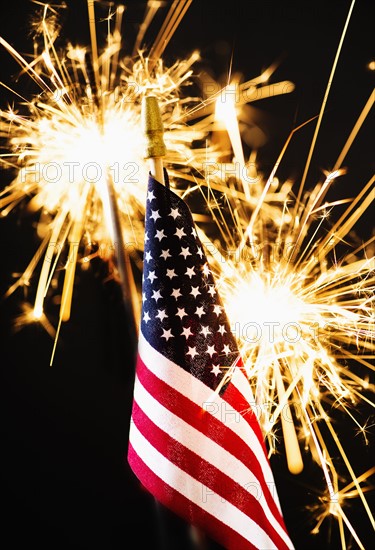 Sparkler and American flag an black background.