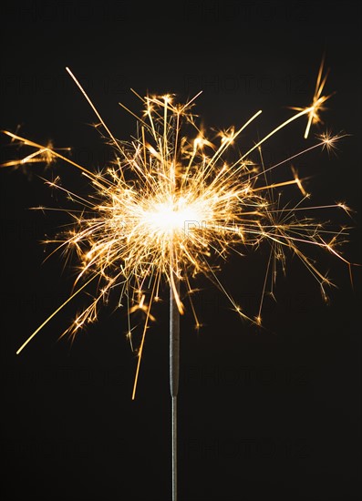 Burning sparkler on black background.