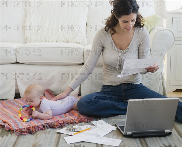 Mother with baby boy (2-5 months) sorting home finances. Photo : Jamie Grill